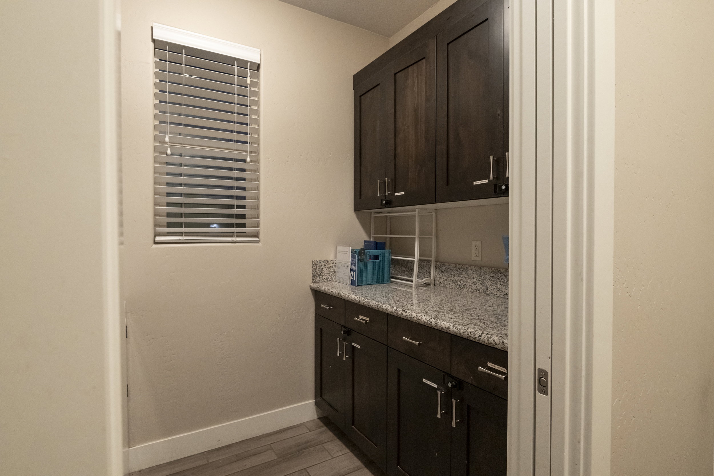 Bar featuring dark wood finish cabinets, light stone countertops, and light wood-style flooring