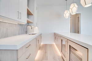 Kitchen featuring open shelves, light wood finished floors, light stone countertops, hanging light fixtures, and modern cabinets