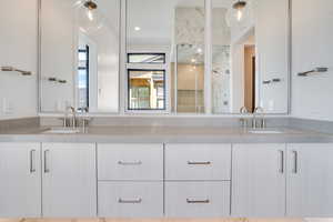 Bathroom with double vanity and a marble finish shower