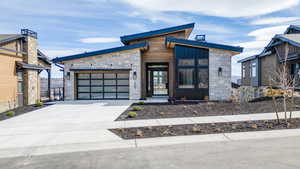 Contemporary house with stone siding, a garage, and concrete driveway