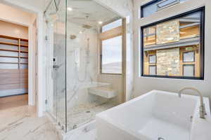 Full bathroom featuring a marble finish shower, a freestanding tub, a spacious closet, and light marble finish flooring
