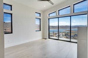 Primary Bedroom featuring a water and mountain view, a ceiling fan, healthy amount of natural light, light wood-type flooring, and recessed lighting