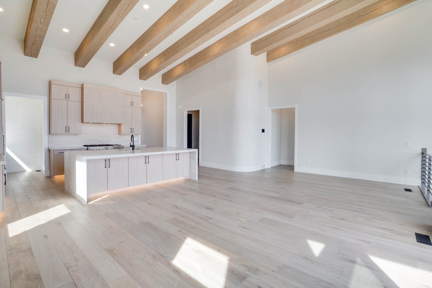 Kitchen featuring light wood finish cabinets, open floor plan, an island with sink, recessed lighting, and decorative backsplash