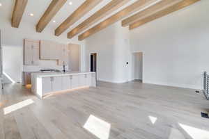 Kitchen featuring light wood finish cabinets, open floor plan, an island with sink, recessed lighting, and decorative backsplash