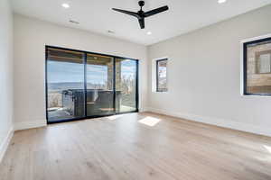 Empty room with ceiling fan, light wood finished floors, and recessed lighting