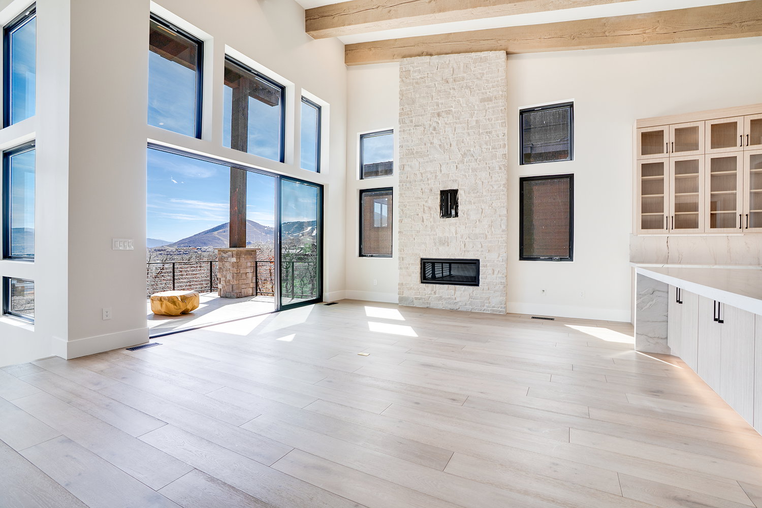 Unfurnished living room with a mountain view, a stone fireplace, light wood-type flooring, and lofted ceiling