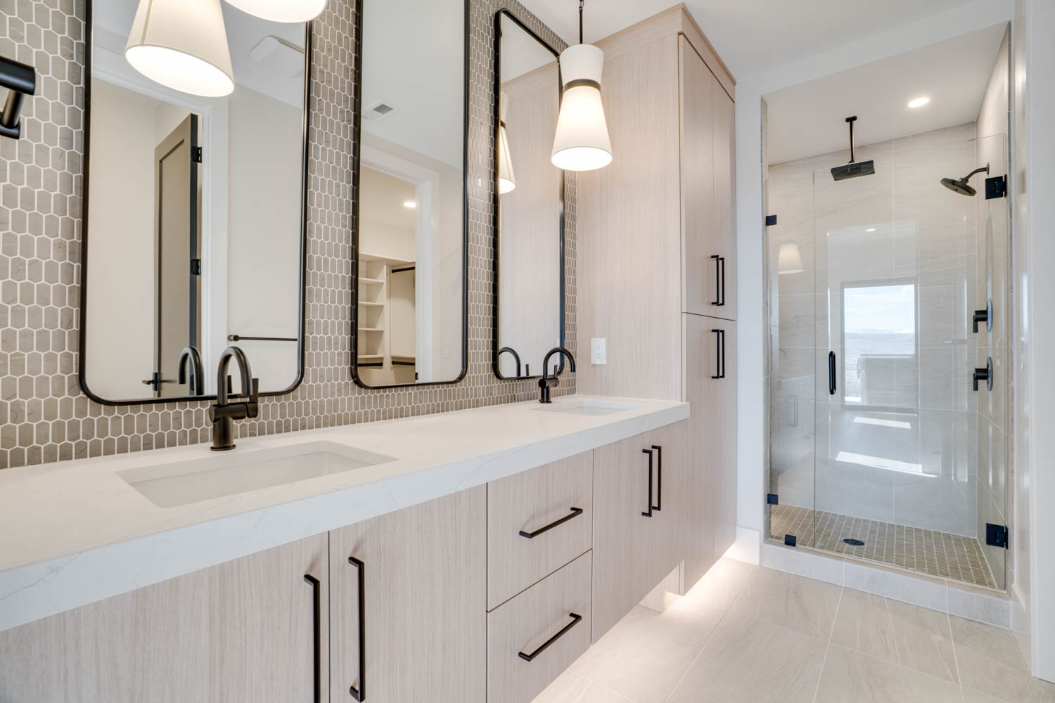 Full bath with double vanity, a stall shower, and light tile patterned floors