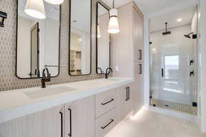 Full bath with double vanity, a stall shower, and light tile patterned floors