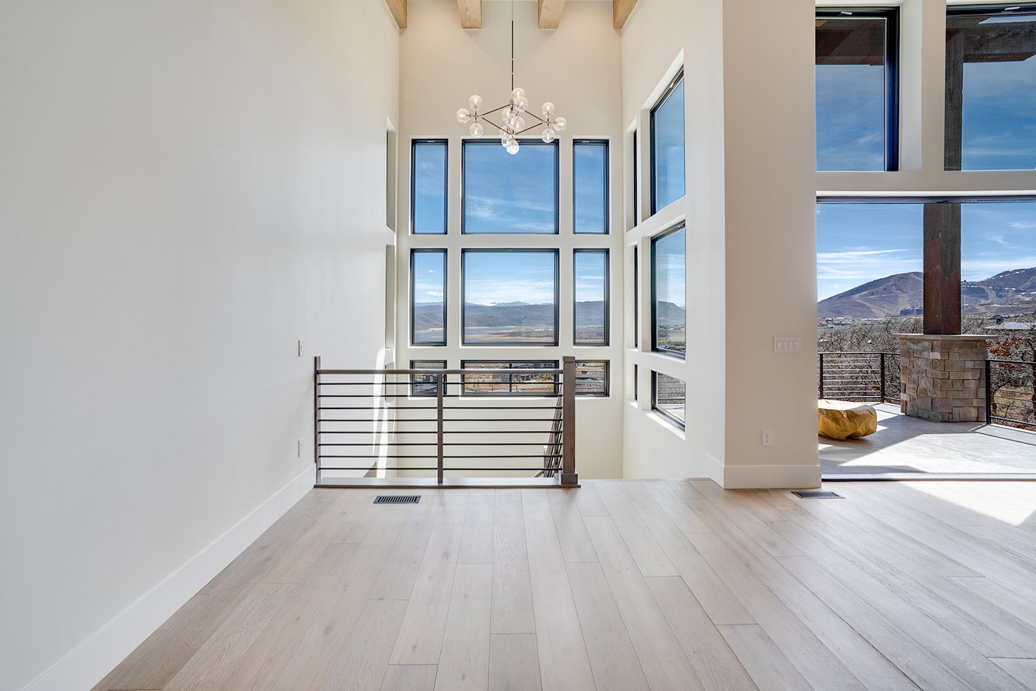 Spare room with a mountain view, light wood finished floors, a chandelier, and a high ceiling