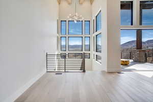Spare room with a mountain view, light wood finished floors, a chandelier, and a high ceiling