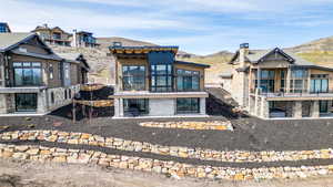 Back of house featuring stone siding, a mountain view, a patio, and a sunroom