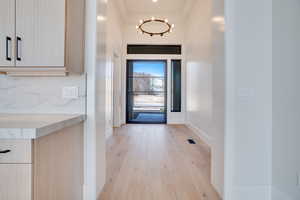 Foyer entrance featuring light wood-style flooring, a high ceiling, and a chandelier