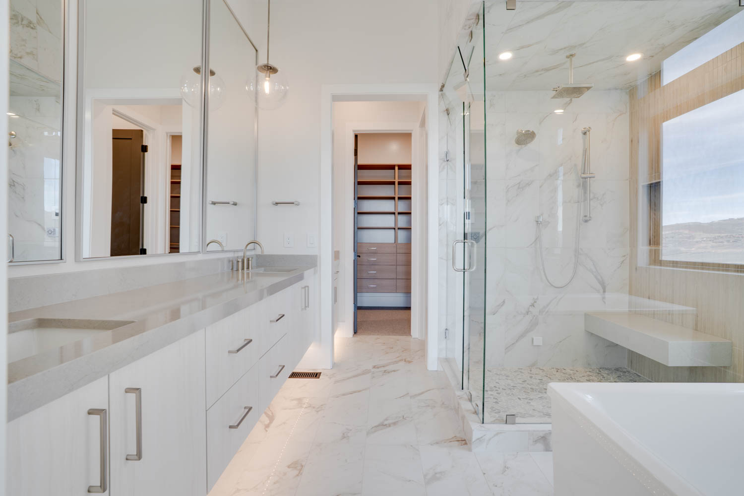 Full bath with a spacious closet, a marble finish shower, double vanity, a freestanding bath, and light marble finish floors