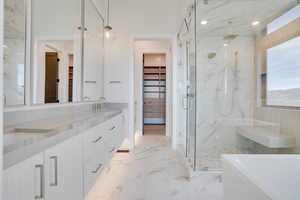 Full bath with a spacious closet, a marble finish shower, double vanity, a freestanding bath, and light marble finish floors