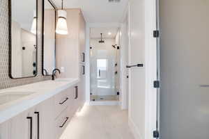 Bathroom with double vanity, a stall shower, and light tile patterned floors