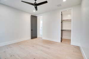 Unfurnished bedroom featuring light wood-style flooring, a walk in closet, recessed lighting, and ceiling fan
