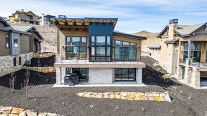 Back of house with a patio, a mountain view, and stone siding