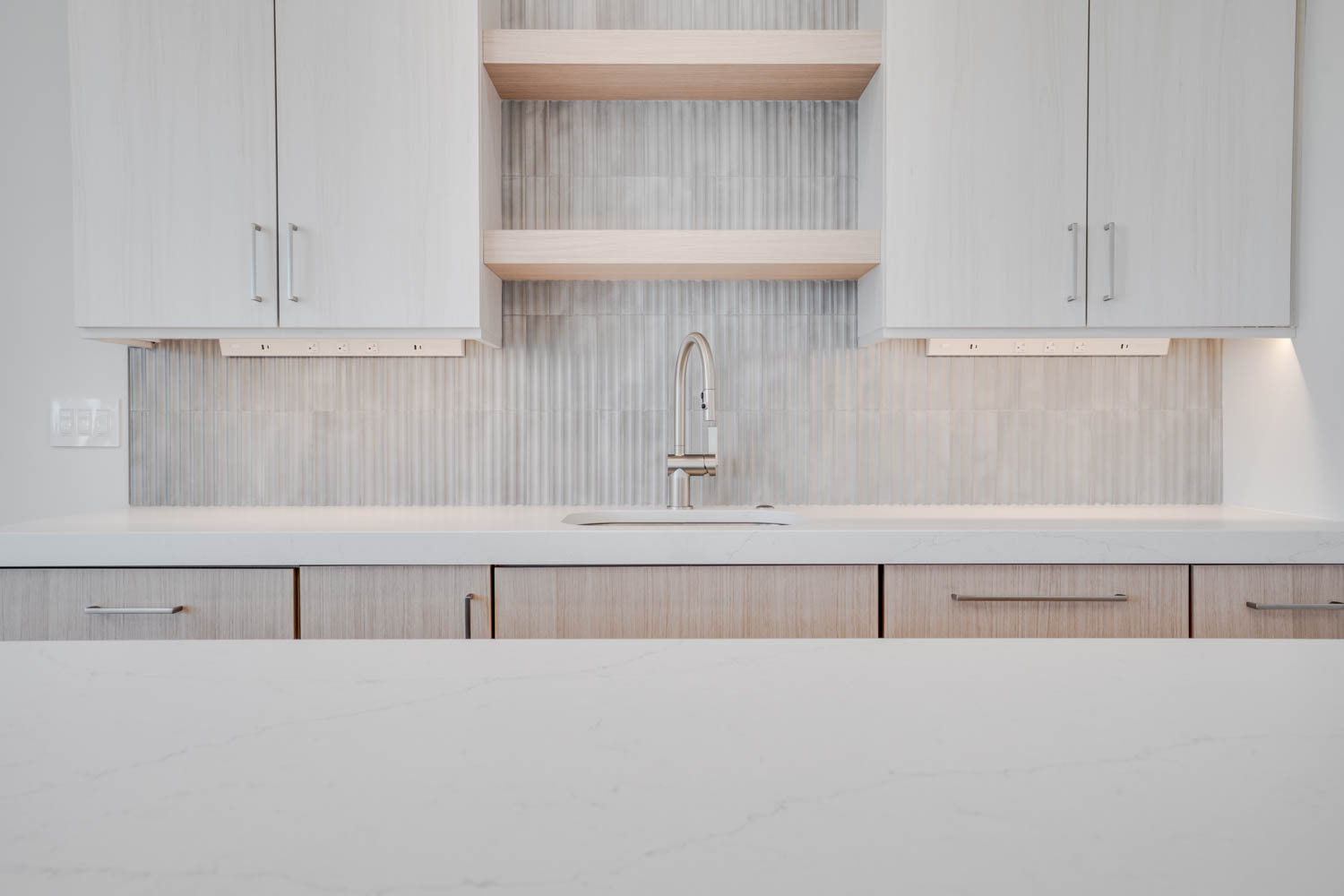 Kitchen featuring open shelves, light stone countertops, decorative backsplash, and light wood finish cabinetry
