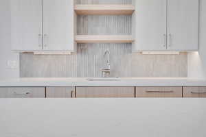 Kitchen featuring open shelves, light stone countertops, decorative backsplash, and light wood finish cabinetry