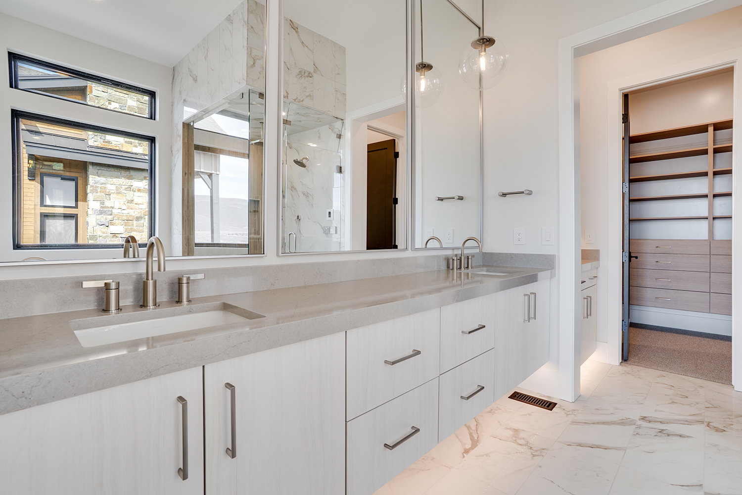 Full bathroom featuring double vanity, a marble finish shower, a spacious closet, and light marble finish floors