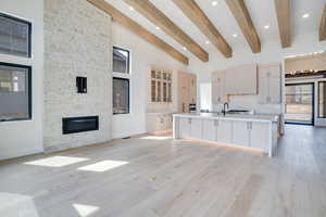 Kitchen with open floor plan, a spacious island, light wood finish cabinets, light wood-type flooring, and vaulted ceiling