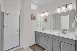 Bathroom with double vanity, a shower stall, and light tile patterned floors