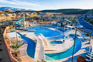 Community pool featuring a community hot tub, a water slide, a patio area, a mountain view, and a residential view