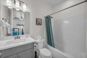 Ensuite bathroom featuring vanity, shower / bath combo with shower curtain, and a ceiling fan