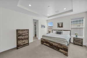 Bedroom with recessed lighting, light carpet, and a raised ceiling