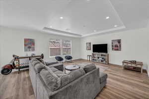 Living room with light wood-type flooring, recessed lighting, and a raised ceiling