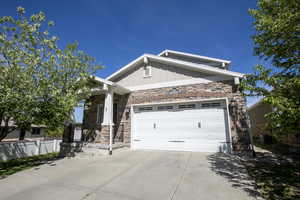 Craftsman house with board and batten siding, stone siding, concrete driveway, and a garage