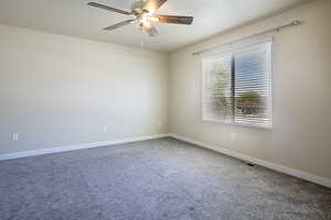 Carpeted empty room with a ceiling fan and baseboards