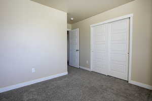 Unfurnished bedroom with dark colored carpet and a closet
