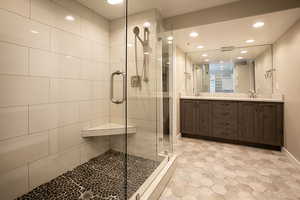 Full bathroom with recessed lighting, double vanity, and a stall shower