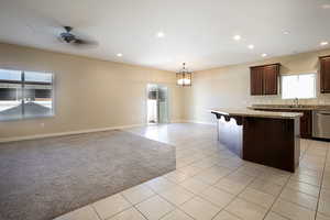 Kitchen featuring a breakfast bar area, ceiling fan, open floor plan, light tile patterned flooring, and dishwasher