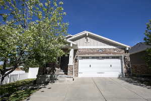Craftsman house featuring board and batten siding, stone siding, an attached garage, and driveway