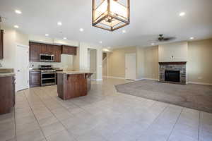 Kitchen featuring open floor plan, light tile patterned floors, a breakfast bar, stainless steel appliances, and a center island