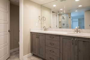 Bathroom featuring double vanity, recessed lighting, a shower stall, and light tile patterned flooring