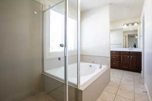 Bathroom with a garden tub, light tile patterned floors, vanity, and a shower stall