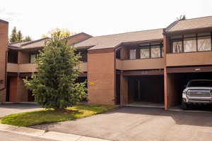 View of front facade with a shingled roof, brick siding, and a balcony