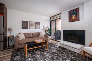 Living room with wood finished floors and a glass covered fireplace