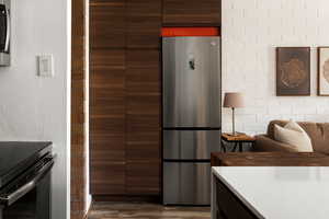 Kitchen featuring dark wood finish cabinets, modern cabinets, freestanding refrigerator, dark wood-type flooring, and black range with electric stovetop