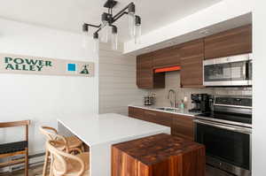Kitchen with stainless steel appliances, modern cabinets, a kitchen bar, and a kitchen island