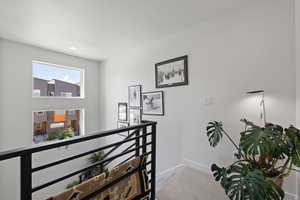 Hallway featuring an upstairs landing, light colored carpet, and recessed lighting