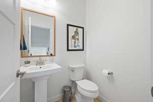 Half bath with toilet and light wood-style floors