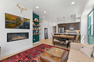 Living room with a glass covered fireplace, recessed lighting, and built in features