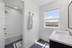 Full bathroom with dark tile patterned flooring, vanity, and bathing tub / shower combination
