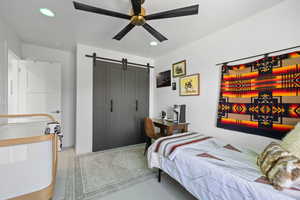 Bedroom with a barn door, a closet, ceiling fan, light colored carpet, and recessed lighting