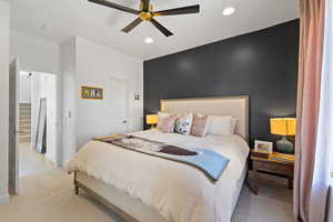 Bedroom with recessed lighting, ceiling fan, light colored carpet, and an accent wall