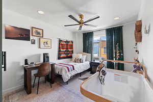 Carpeted bedroom with a ceiling fan and recessed lighting